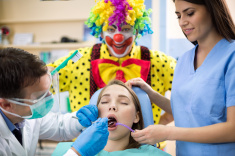 stock-photo-89037369-girl-repair-tooth-in-dental-clinic-with-clown-in-background.jpg
